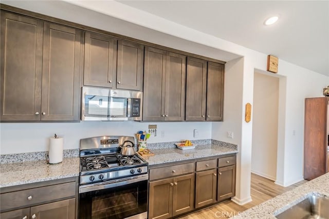 14168 Georgetown St, Hesperia, CA 92344 - kitchen with appliances with stainless steel finishes, light wood-style floors, dark brown cabinets, light stone counters, and baseboards