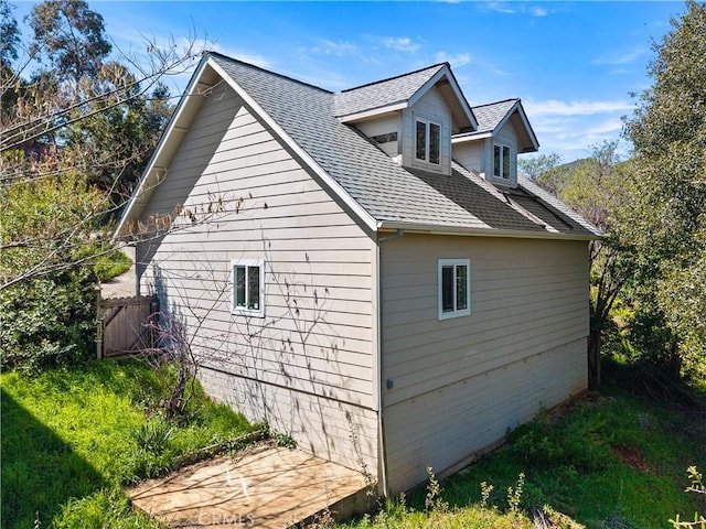view of side of property featuring a shingled roof and fence