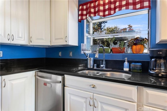 kitchen featuring dark countertops, white cabinets, and a sink
