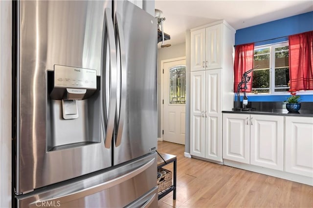 kitchen featuring stainless steel fridge with ice dispenser, white cabinetry, light wood-style flooring, and dark countertops