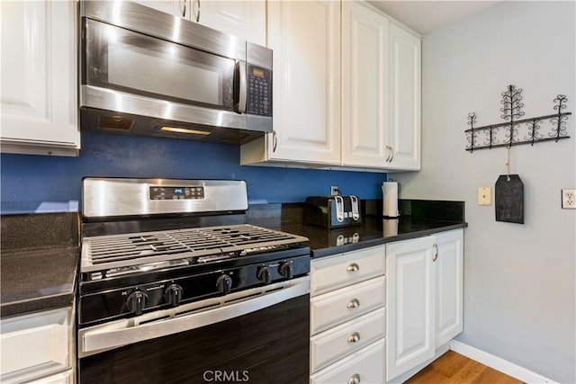 kitchen with baseboards, white cabinets, dark countertops, and appliances with stainless steel finishes