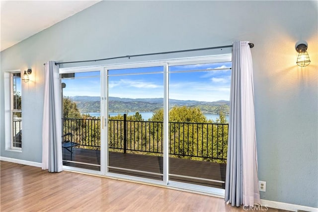 doorway to outside with baseboards, vaulted ceiling, wood finished floors, and a water and mountain view