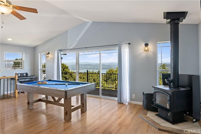 rec room with pool table, a wealth of natural light, light wood-style flooring, and a wood stove