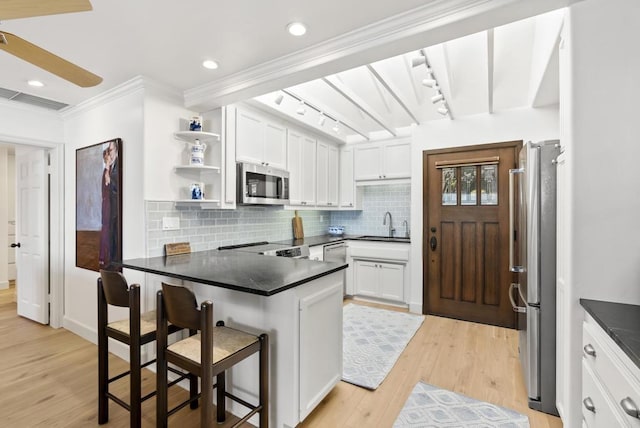 1552 Camino Del Mar Unit 623/625, Del Mar, CA 92014 - kitchen featuring appliances with stainless steel finishes, a peninsula, white cabinetry, light wood-style floors, and decorative backsplash