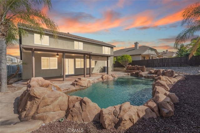 27077 Calendula St, Corona, CA 92883 - pool at dusk with a fenced in pool, a patio area, a fenced backyard, and a ceiling fan