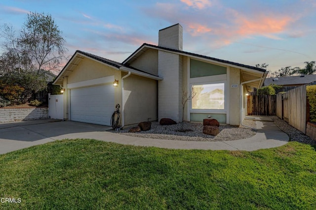view of front of property with fence, an attached garage, driveway, a yard, and a chimney