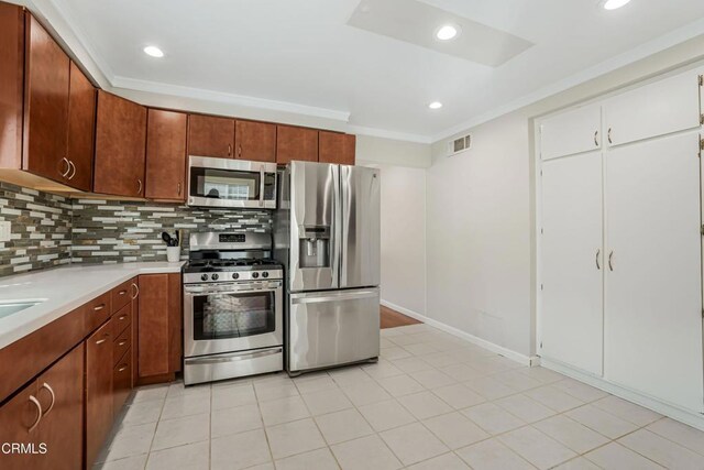 kitchen with light countertops, stainless steel appliances, visible vents, decorative backsplash, and ornamental molding