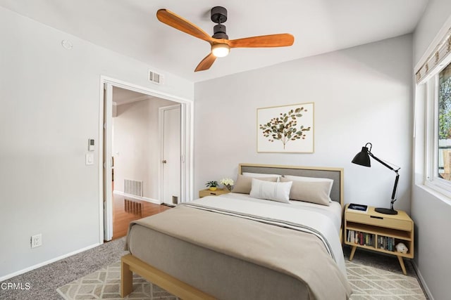 carpeted bedroom featuring baseboards, visible vents, and ceiling fan