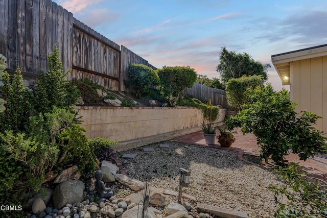 yard at dusk with a patio and a fenced backyard