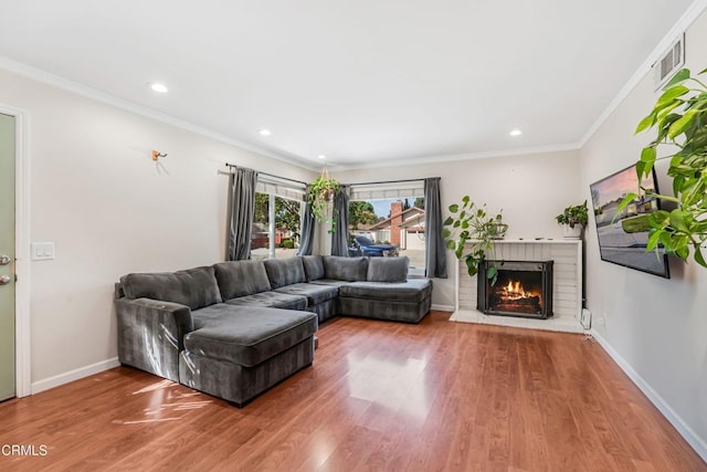 living area with a fireplace, wood finished floors, baseboards, ornamental molding, and recessed lighting