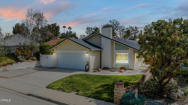 view of front of house with fence, an attached garage, a chimney, stucco siding, and driveway