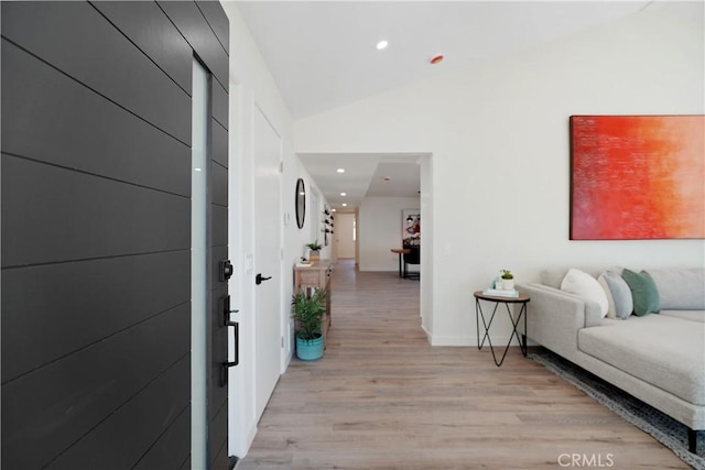 hallway featuring light wood-type flooring, baseboards, recessed lighting, and lofted ceiling
