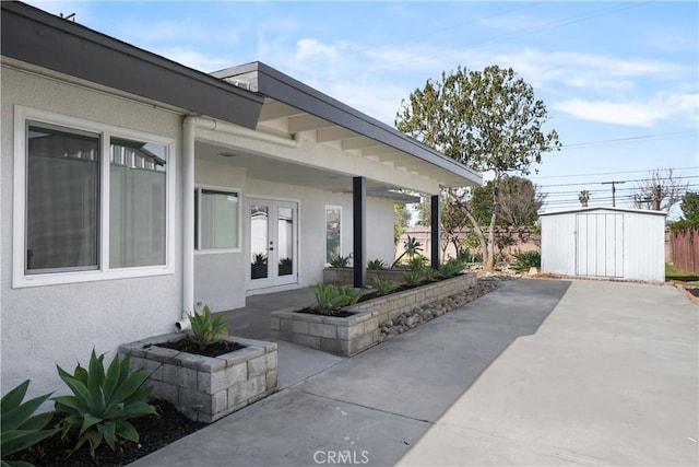 entrance to property featuring fence, a patio, french doors, and stucco siding