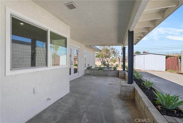 view of patio featuring an outdoor structure, fence, and visible vents