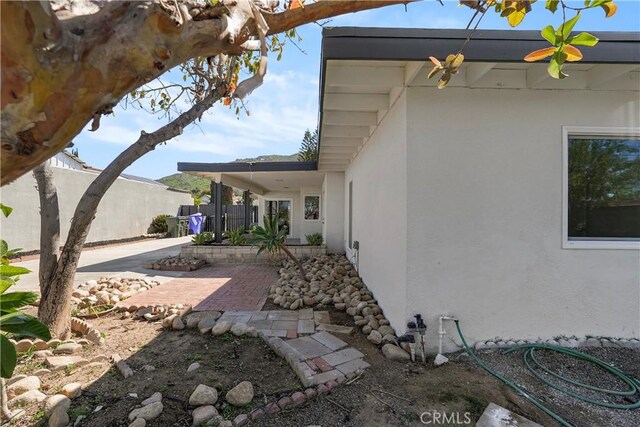 view of side of home with a patio, stucco siding, and fence
