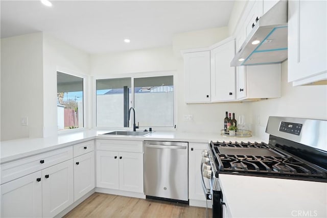 kitchen with recessed lighting, white cabinets, under cabinet range hood, a sink, and appliances with stainless steel finishes