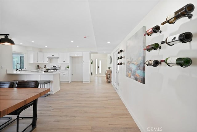 corridor with recessed lighting, light wood-type flooring, baseboards, and a sink