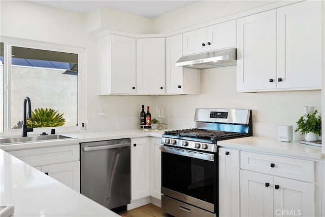 kitchen featuring light countertops, under cabinet range hood, stainless steel appliances, and a sink