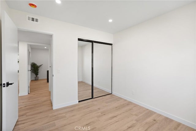 unfurnished bedroom with a closet, light wood-style floors, baseboards, visible vents, and recessed lighting