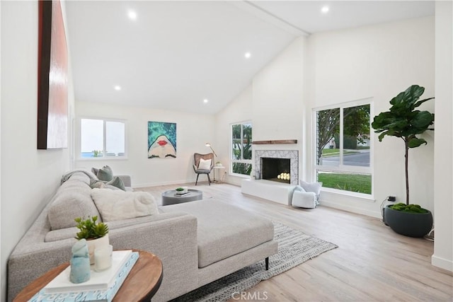 living room with recessed lighting, a fireplace with raised hearth, wood finished floors, baseboards, and high vaulted ceiling