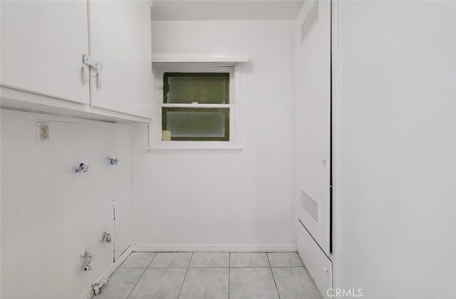 laundry area featuring baseboards, visible vents, hookup for a gas dryer, cabinet space, and light tile patterned floors