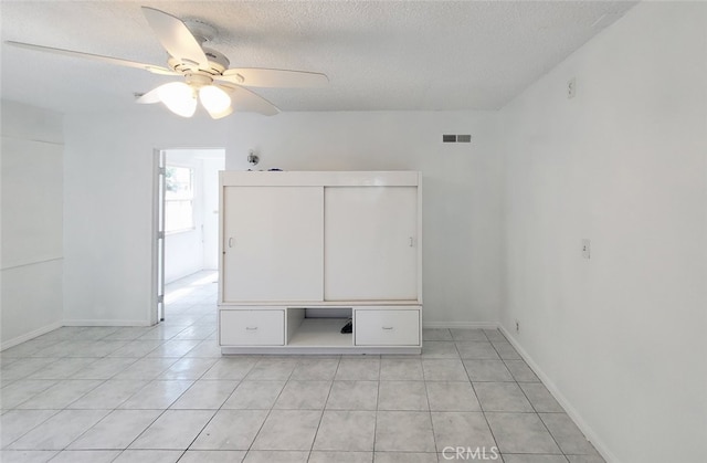 spare room featuring a textured ceiling, visible vents, and light tile patterned floors