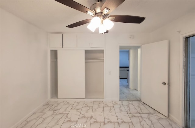 unfurnished bedroom featuring a closet, marble finish floor, baseboards, and ceiling fan