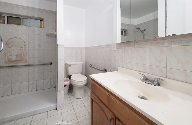 bathroom with toilet, wainscoting, tiled shower, tile patterned flooring, and vanity