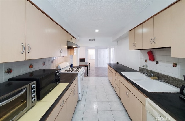 kitchen with a sink, a textured ceiling, white appliances, backsplash, and visible vents