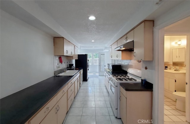 1020 E Rowland Ave, West Covina, CA 91790 - kitchen with white gas range oven, under cabinet range hood, dark countertops, backsplash, and recessed lighting