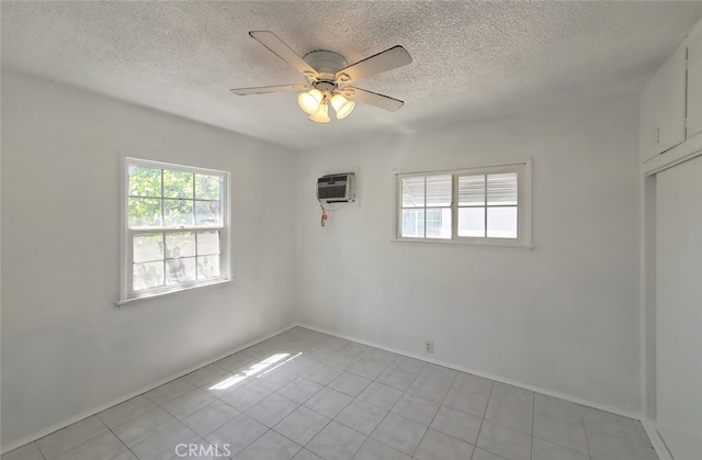 spare room with a ceiling fan, a textured ceiling, a wall mounted AC, light tile patterned floors, and baseboards