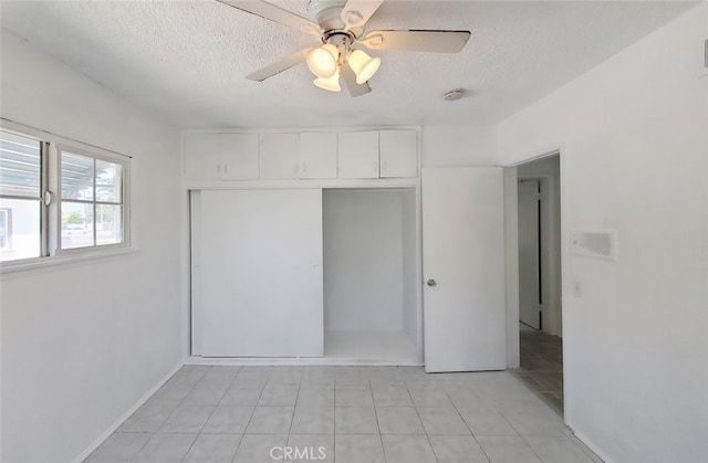 unfurnished bedroom featuring light tile patterned floors, a textured ceiling, and a closet