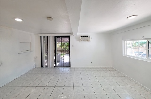 unfurnished room with a wealth of natural light, a wall mounted AC, and light tile patterned floors