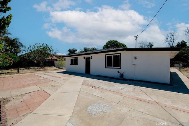 view of front facade with a patio area, stucco siding, and fence