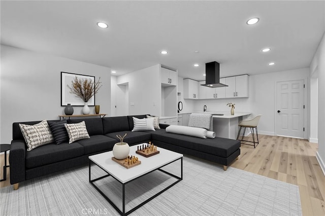 living room with light wood-style floors, baseboards, and recessed lighting