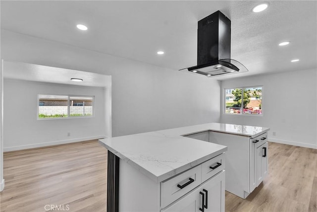 26339 First St, Loma Linda, CA 92318 - kitchen with wall chimney range hood, light wood finished floors, white cabinets, plenty of natural light, and recessed lighting