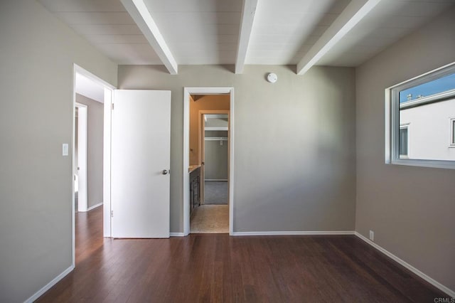 unfurnished room featuring baseboards, beam ceiling, and wood finished floors