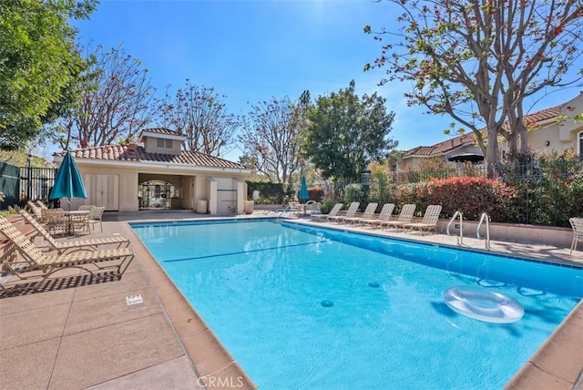 community pool with fence and a patio area
