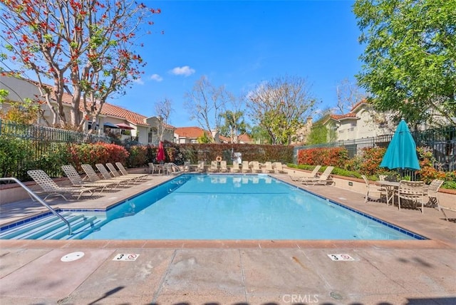 pool with fence, a patio, and a residential view