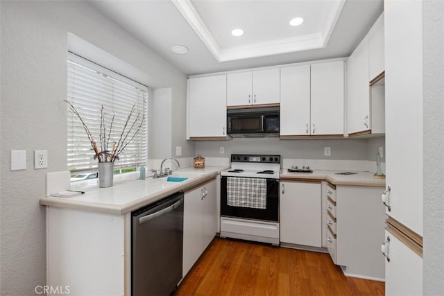 kitchen featuring electric range, black microwave, wood finished floors, dishwasher, and a sink