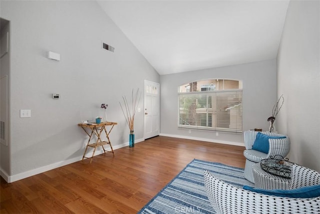 sitting room with baseboards, high vaulted ceiling, wood finished floors, and visible vents