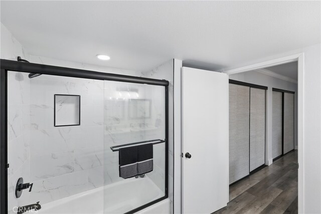 full bathroom with crown molding, recessed lighting, wood finished floors, and bath / shower combo with glass door