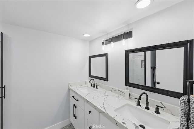 bathroom with a sink, baseboards, a shower with shower door, and double vanity