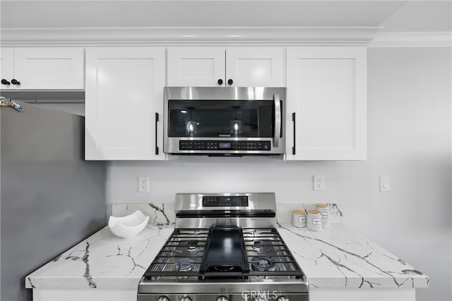 kitchen featuring crown molding, white cabinets, light stone countertops, and stainless steel appliances