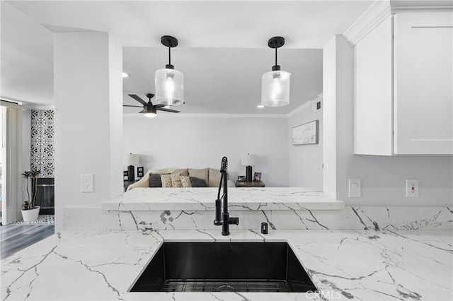 kitchen featuring light stone countertops, ceiling fan, a sink, white cabinetry, and ornamental molding