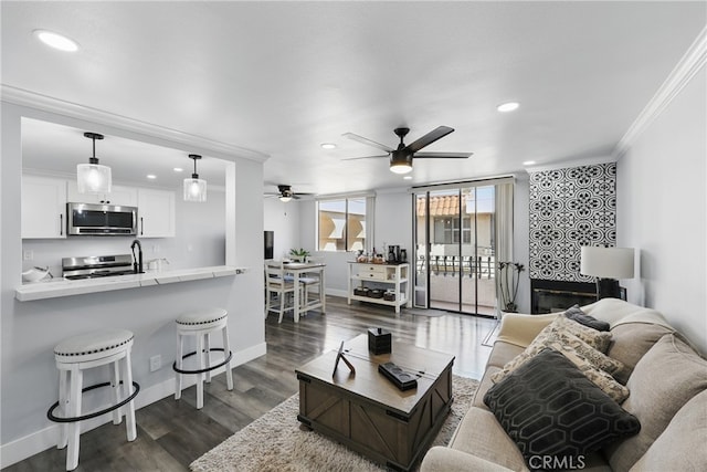 living room with crown molding, recessed lighting, ceiling fan, and dark wood-type flooring