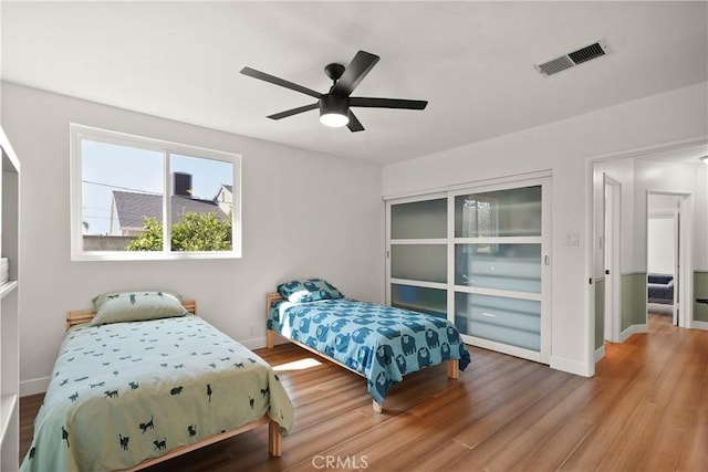 bedroom featuring wood finished floors, ceiling fan, baseboards, and visible vents