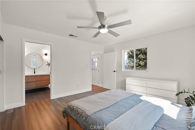 bedroom featuring visible vents, baseboards, connected bathroom, and wood finished floors