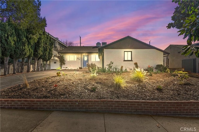 ranch-style home featuring driveway and stucco siding
