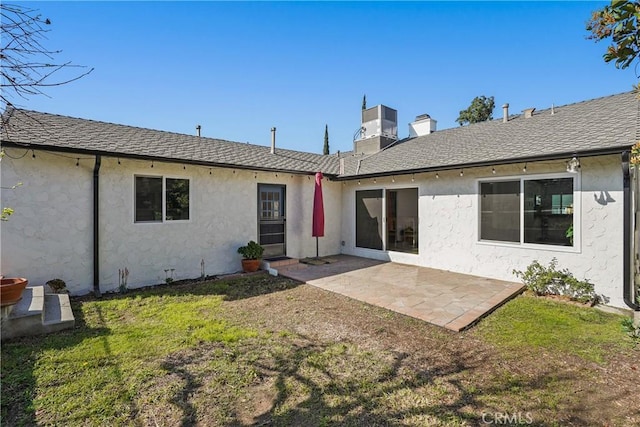 rear view of house featuring central AC unit, a yard, a chimney, a patio, and stucco siding